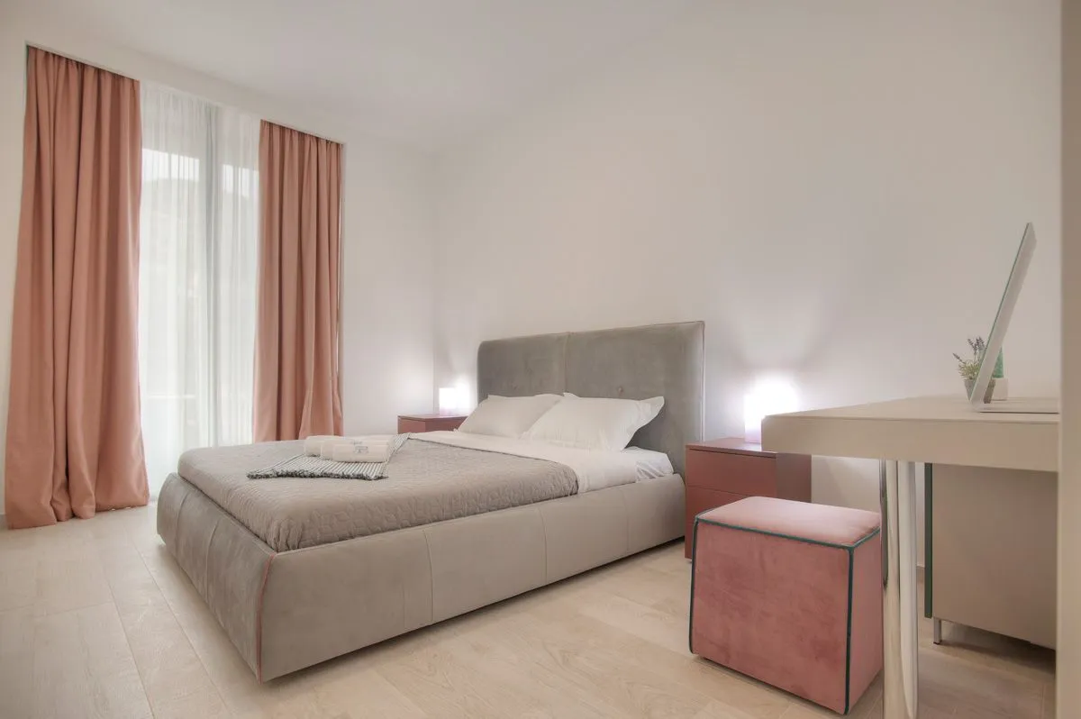 Bright bedroom with a double bed and pink curtains.