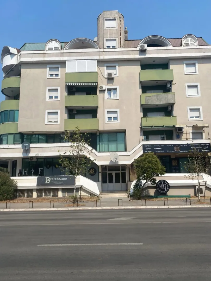 Front facade of a residential and commercial building with balconies and ground floor business premises.