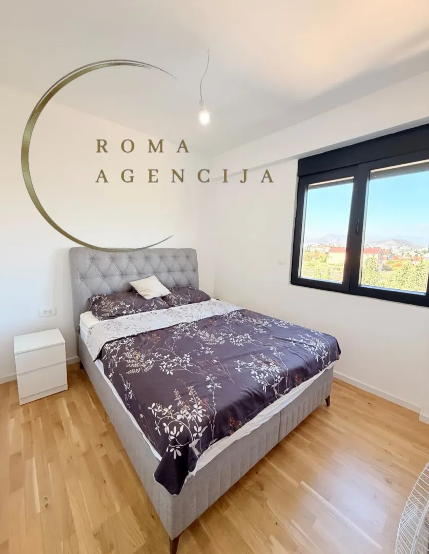 Modern bedroom with a double bed and a view through the window.