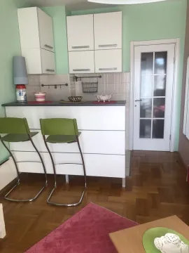 A kitchen with a bar counter and two green bar stools. - image 6