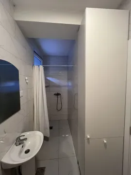 Malo kupatilo sa tušem i bijelim ormarom. - image 7