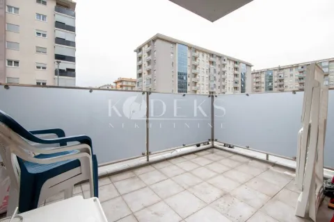 Small tiled balcony with plastic chairs and a view of buildings. - image 11