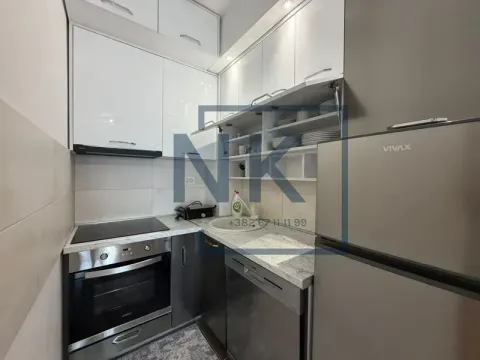 Small kitchen with white and grey-silver cabinets, sink, oven, and refrigerator. - image 3