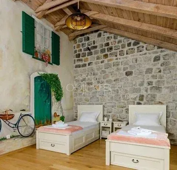 Bedroom with two single beds, a stone wall, and a wooden ceiling.