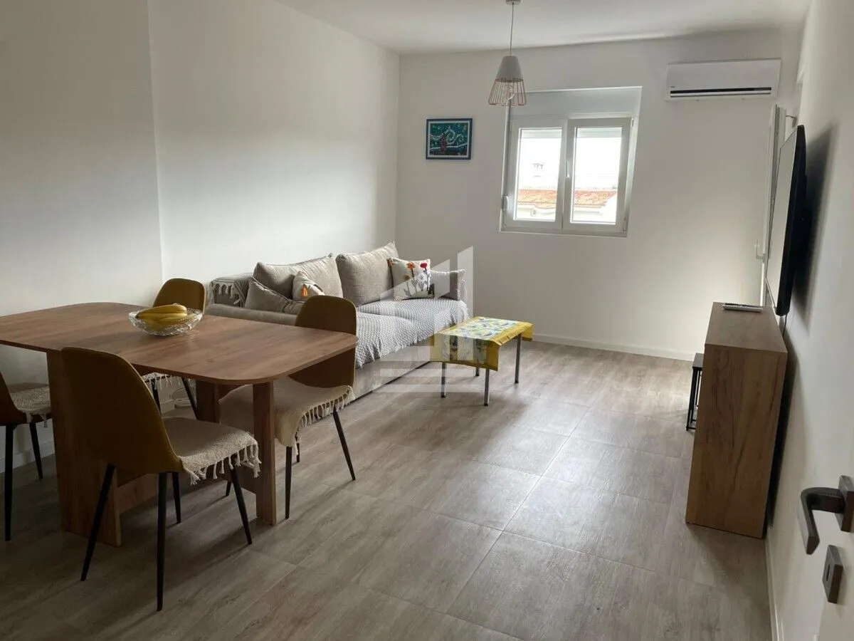 Living room with dining area, sofa, and a wooden table with chairs.