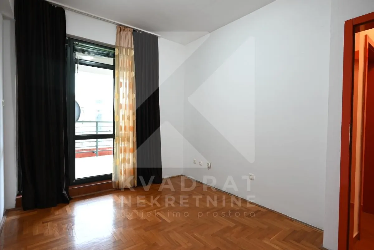 Empty room with parquet flooring and balcony access.