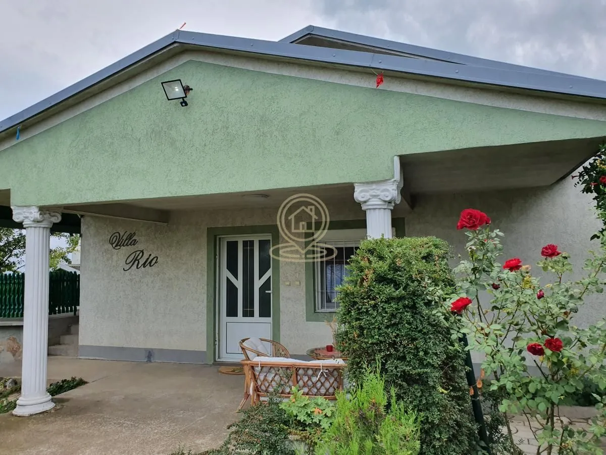 Prednji deo kuće sa natkrivenom terasom i ulaznim vratima.