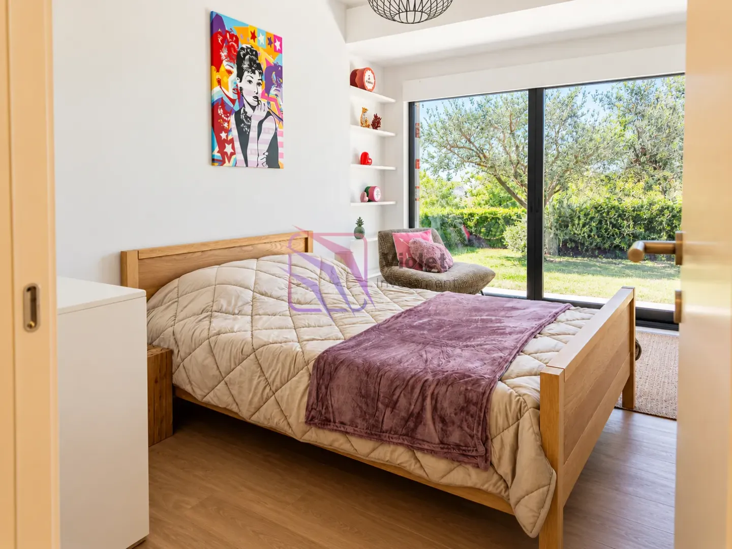 Bedroom with a wooden bed and a large window overlooking the yard.