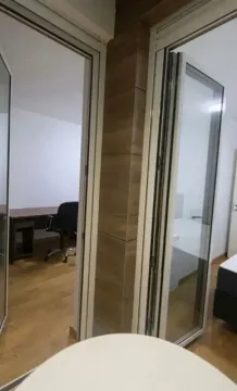 View from a room through glass doors into an office and bedroom. - image 8