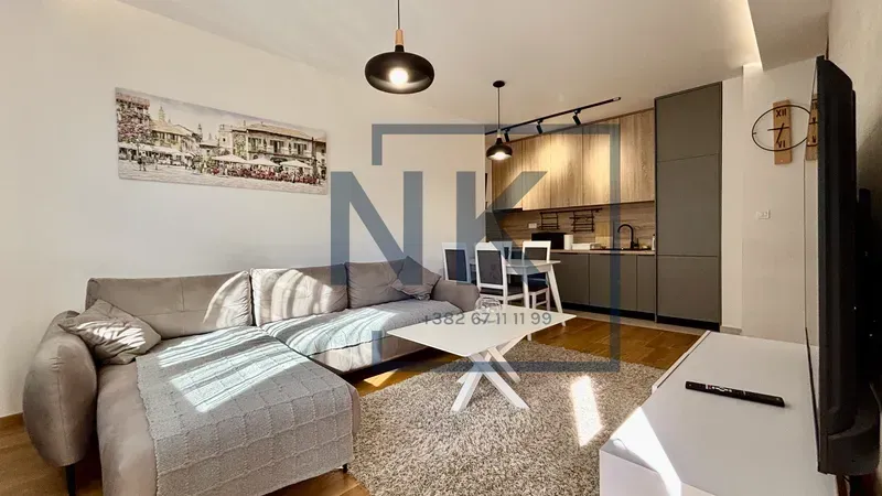 Living room with a sofa, coffee table, and an open-plan kitchen and dining area.