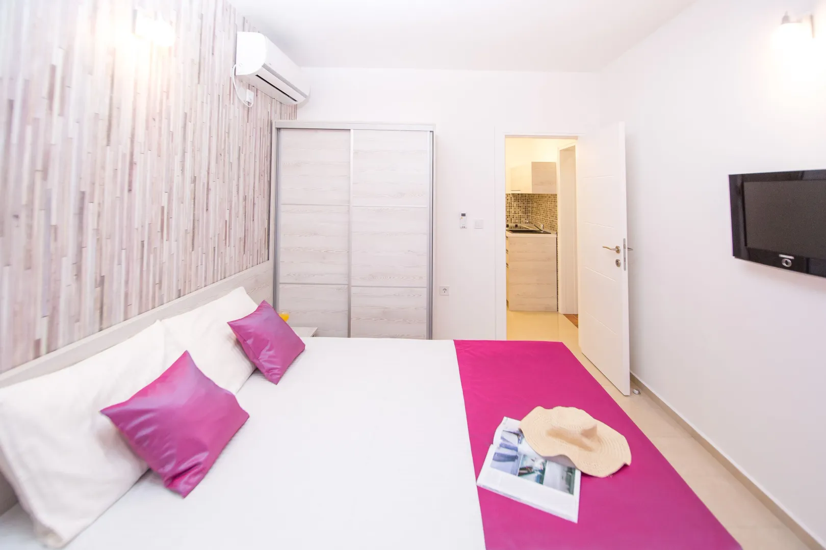 Furnished bedroom with a double bed, wardrobe, and television.