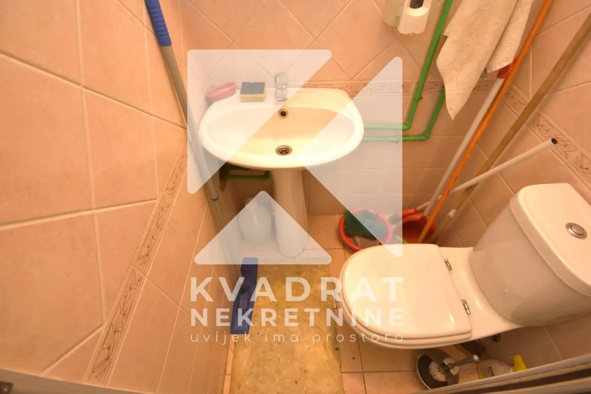 Small bathroom with a sink and toilet tiled with ceramic tiles.