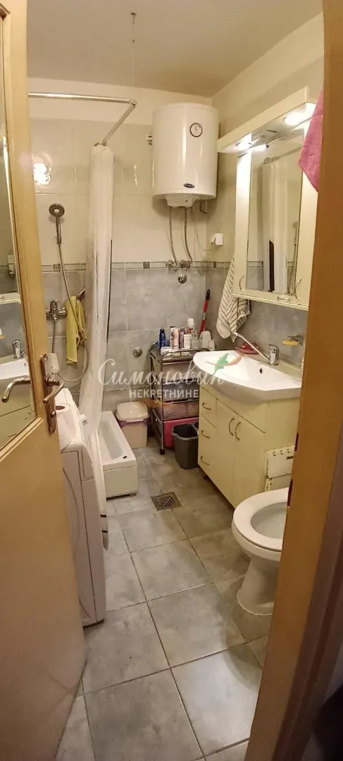 Pogled na kupatilo sa umivaonikom, WC šoljom, tuš kabinom i bojlerom.