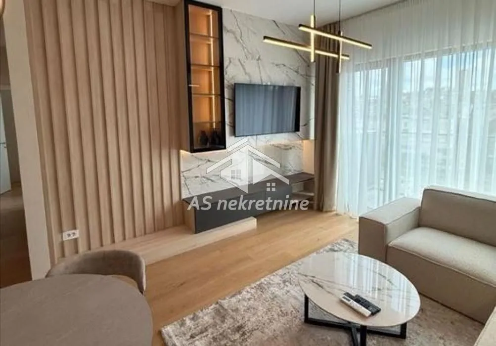 Modern living room with a sofa, TV wall unit, and dining table.
