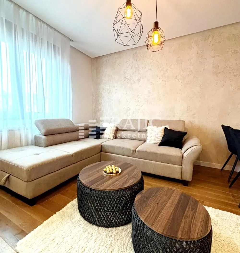Living room with a sectional sofa, coffee tables, and modern lighting.