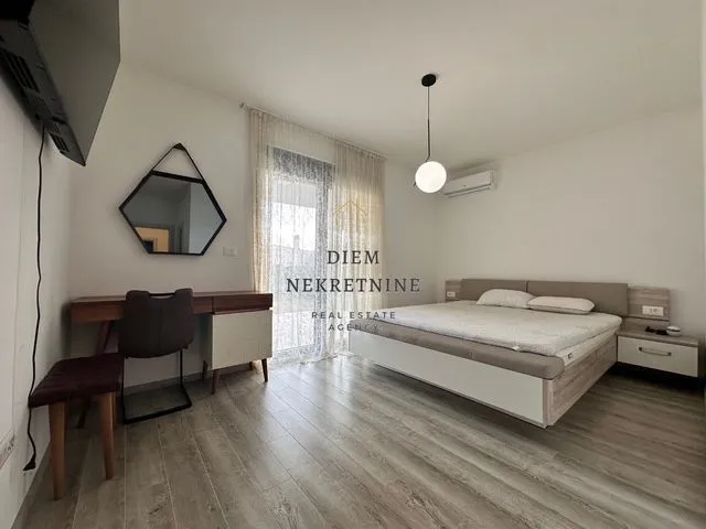 Furnished bedroom with a double bed, desk, and mirror.