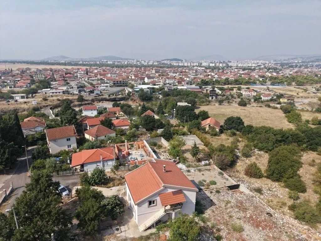 Pogled iz vazduha na kuću sa dvorištem i okolno naselje.