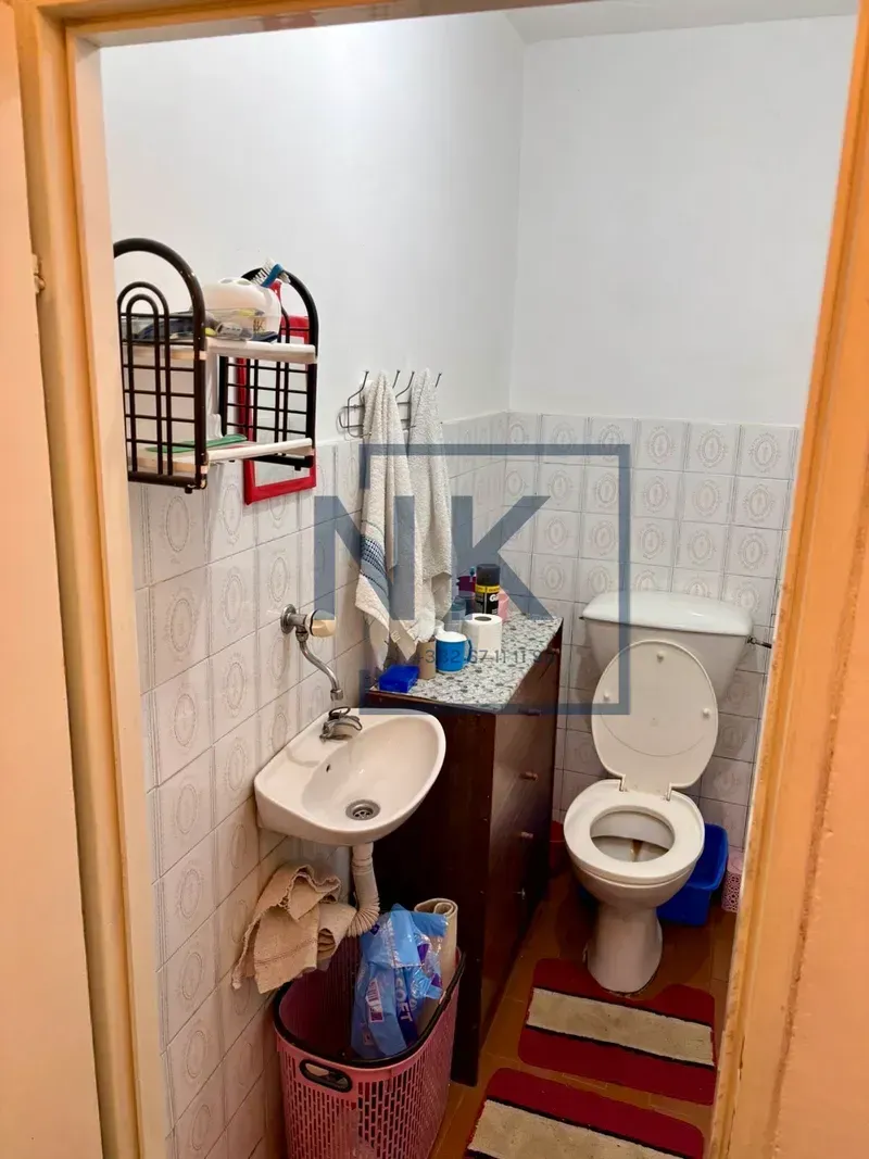Manje kupatilo sa umivaonikom, WC šoljom i zidnim pločicama.