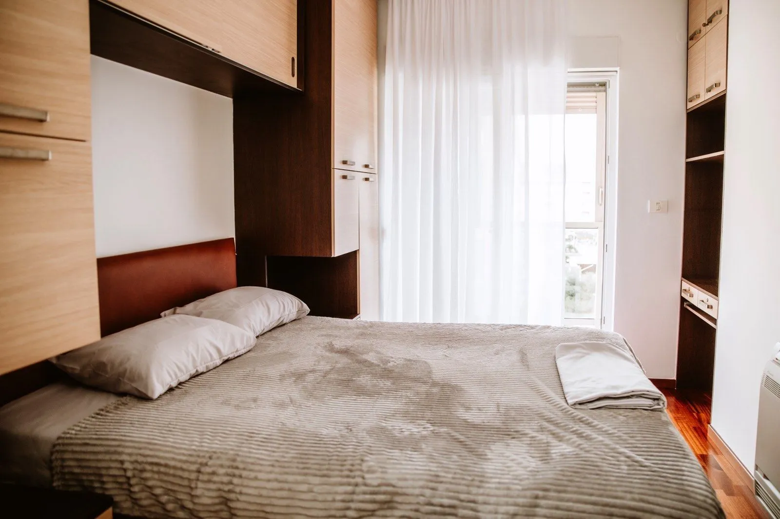 Bright bedroom with built-in wardrobes and access to a balcony.