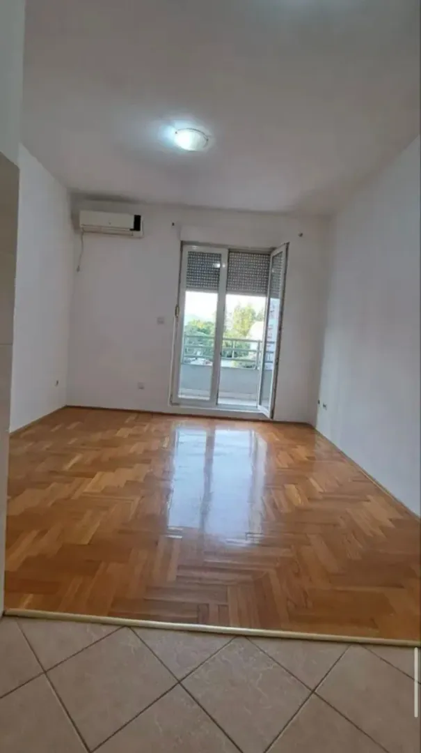 Prazna soba sa parketom i izlazom na terasu.