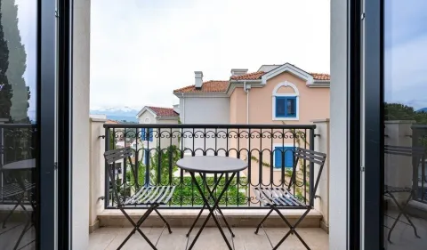 Namješten balkon sa stolom i dvije stolice i pogledom na naselje. - image 8