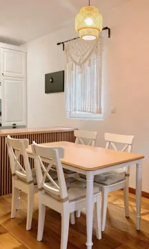 Trpezarija sa drvenim stolom, bijelim stolicama i lusterom. - image 7
