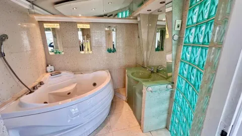 Bathroom equipped with a corner bathtub, vanity sink, and decorative glass blocks. - image 12