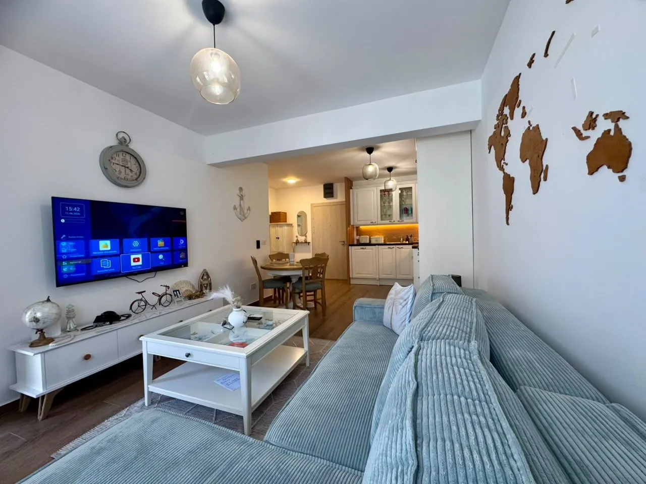 Spacious living room with a sofa, TV, and a view towards the dining area and kitchen.