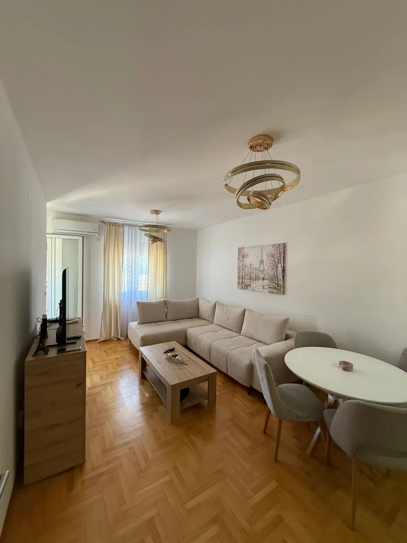 Living room with sofa, dining table, and parquet flooring.