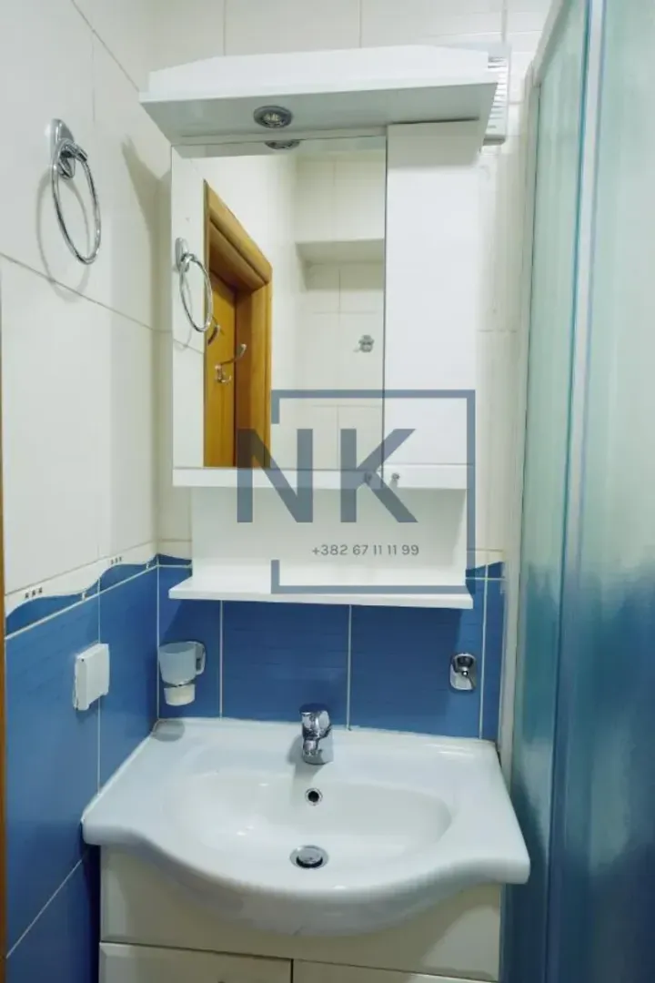 Bathroom with a sink, mirrored cabinet and blue tiles.