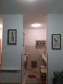 View of a small and functional kitchen through a passageway decorated with framed art. - image 5