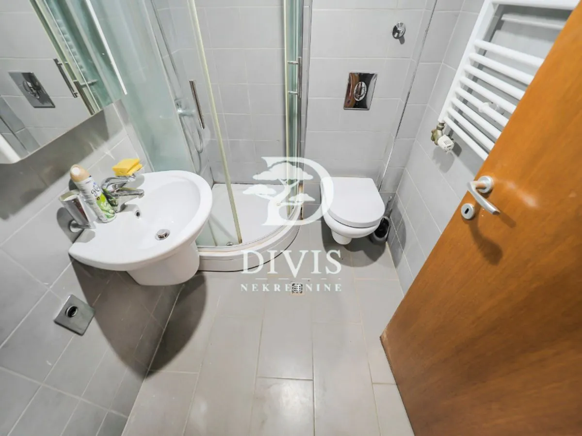 Smaller bathroom with a shower cabin, washbasin, and toilet.