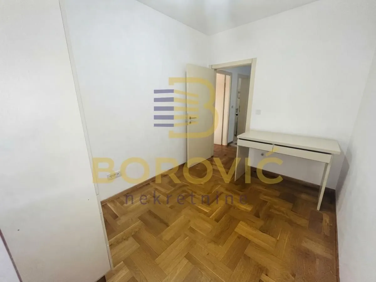 Empty room with parquet flooring and a desk.