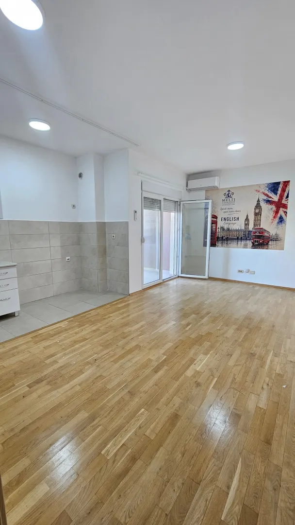 Empty room with wooden flooring, tiled section, and access to the terrace.
