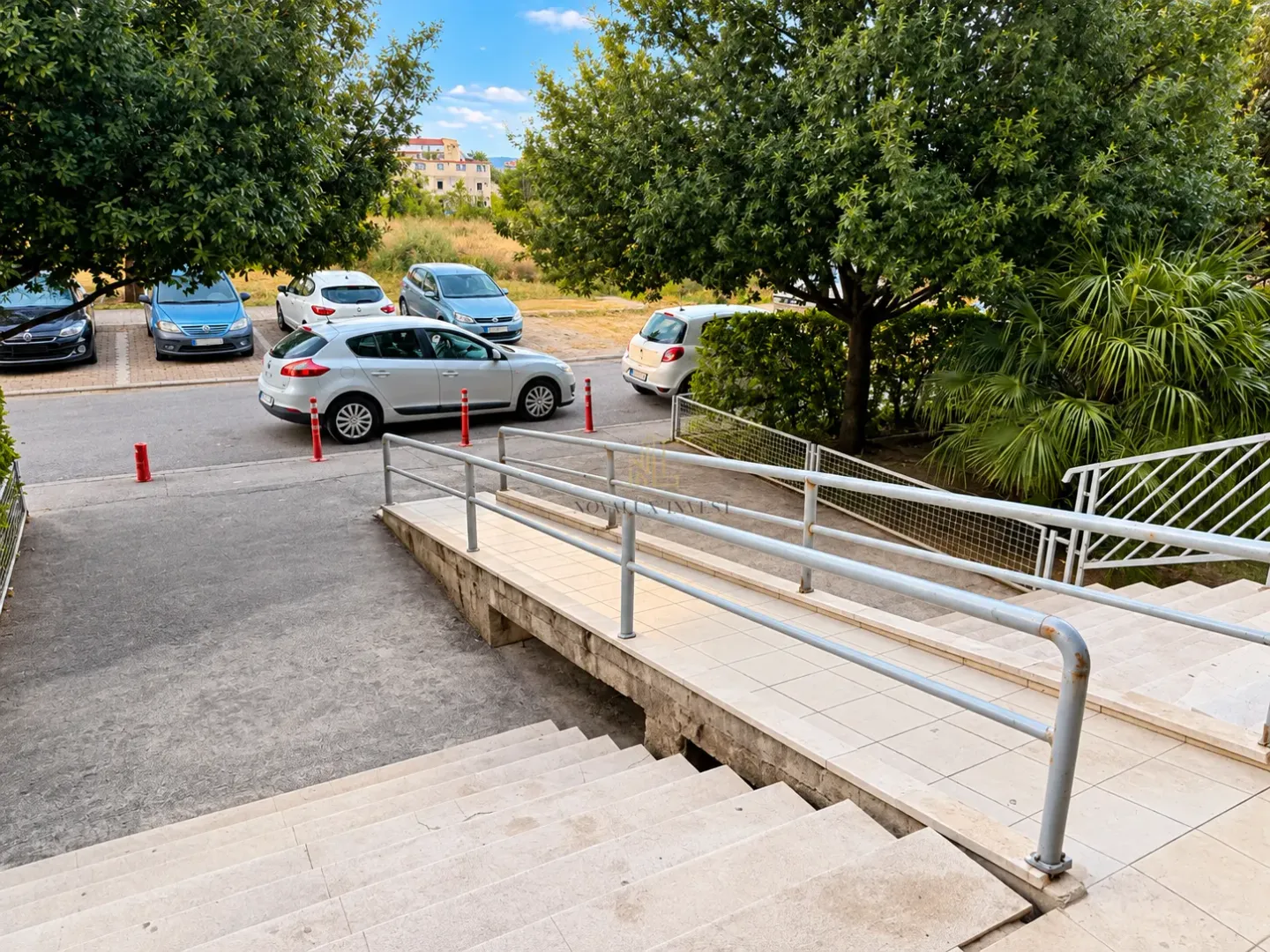 View of the building entrance with stairs and an access ramp.