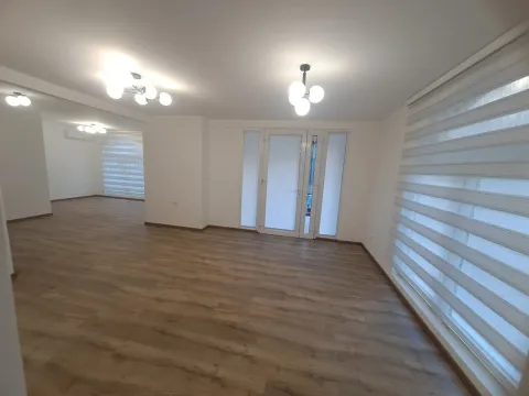 Empty spacious living room with wooden flooring and large windows. - image 2