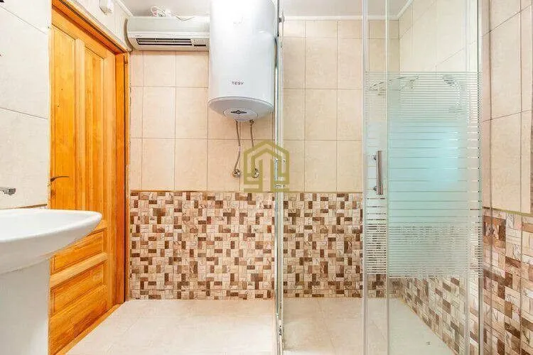Small tiled bathroom with a shower cabin and water heater.