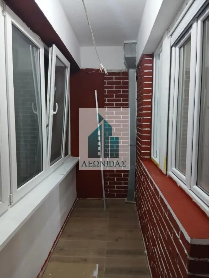 Zastakljeni balkon sa keramičkim podom i zidovima obloženim dekorativnom ciglom.