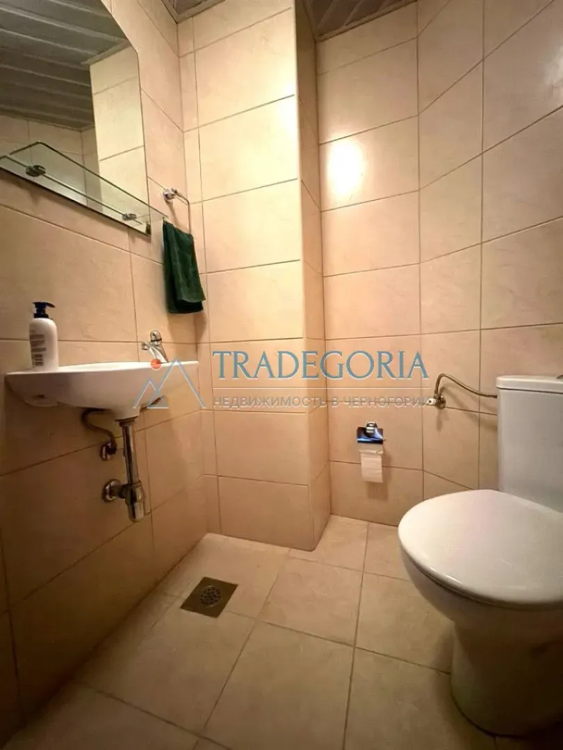 Manje kupatilo obloženo keramičkim pločicama sa umivaonikom i wc šoljom.