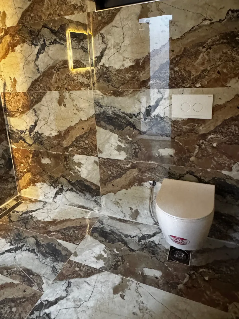Moderne kupatilo sa zidnim pločicama u imitaciji mermera i konzolnom wc šoljom.