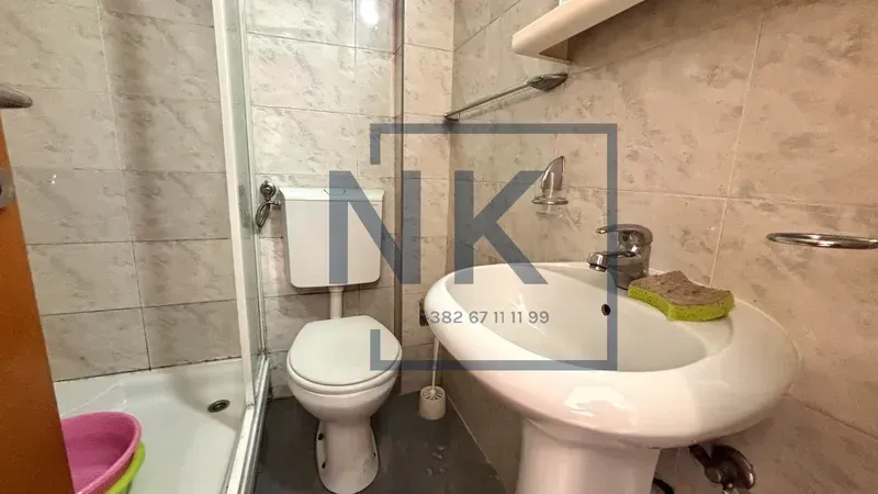 Smaller bathroom with a shower cabin, washbasin, and toilet.