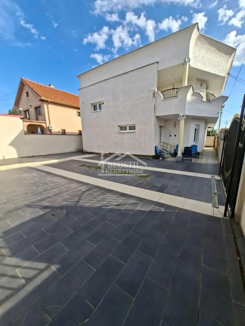 Pogled na dvorište i spoljašnjost kuće sa popločanim platoom.