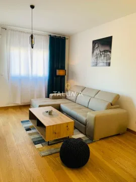 Dnevna soba opremljena ugaonom garniturom, drvenim stočićem i dekorativnim elementima. - image 3