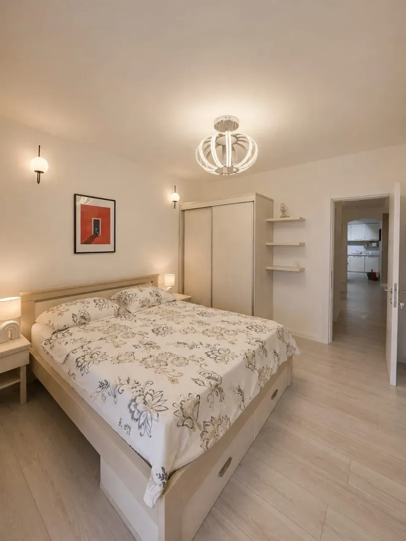 Furnished bedroom with a double bed, wardrobe, and lighting.