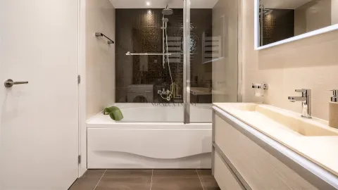 Modern bathroom with a bathtub, glass screen, and washbasin. - image 14