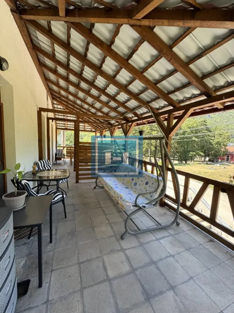 Covered terrace with wooden construction, seating furniture, and a swing.