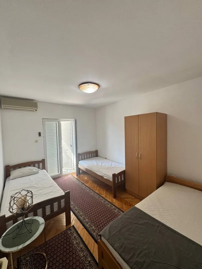 Bedroom with three wooden beds, a wardrobe, and balcony doors.