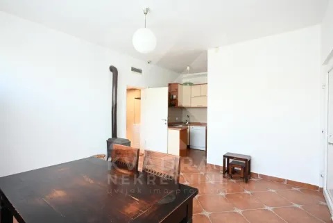 Living room with a dining table and wood stove, looking towards the kitchen in the background. - image 21