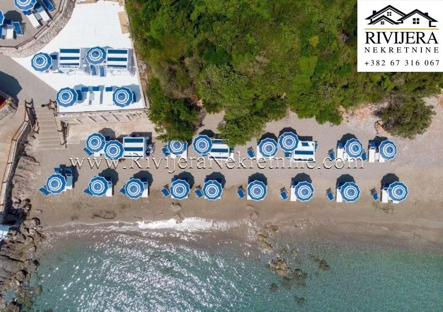 Pogled iz vazduha na uređenu plažu sa suncobranima i ležaljkama pored mora.