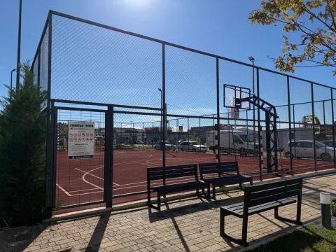 Ograđeni sportski teren sa košem i klupama u dvorištu. - image 17